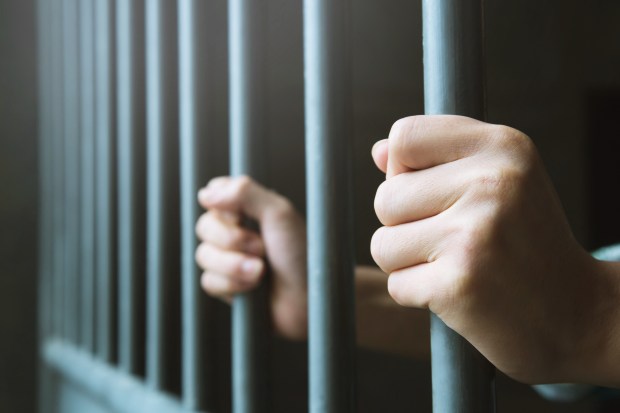 Hands gripping prison bars.