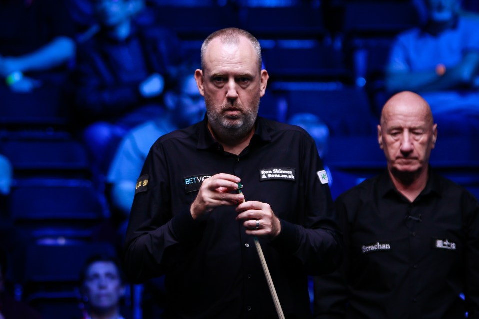 a man in a betvictor shirt holds a pool cue