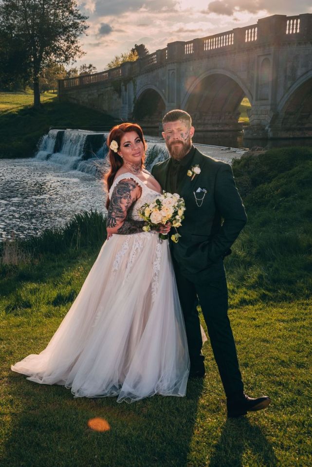 a bride and groom pose in front of a waterfall