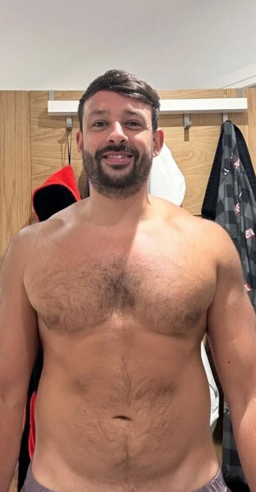 a shirtless man with a beard is smiling in a locker room