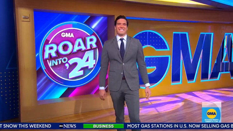 a man in a suit and tie stands in front of a screen that says roar into 24