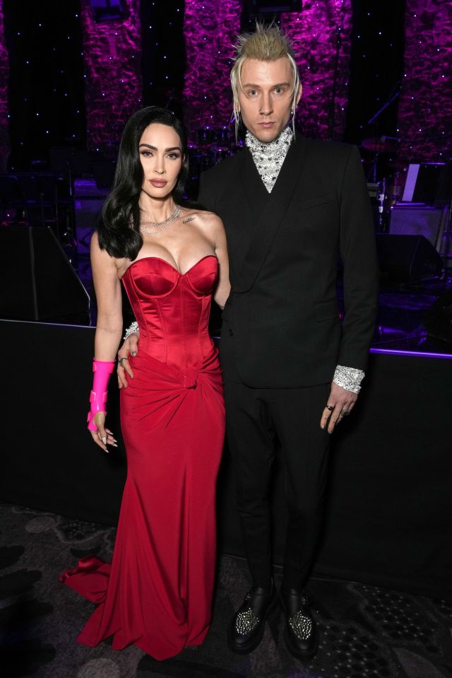 a woman in a red dress stands next to a man in a black suit