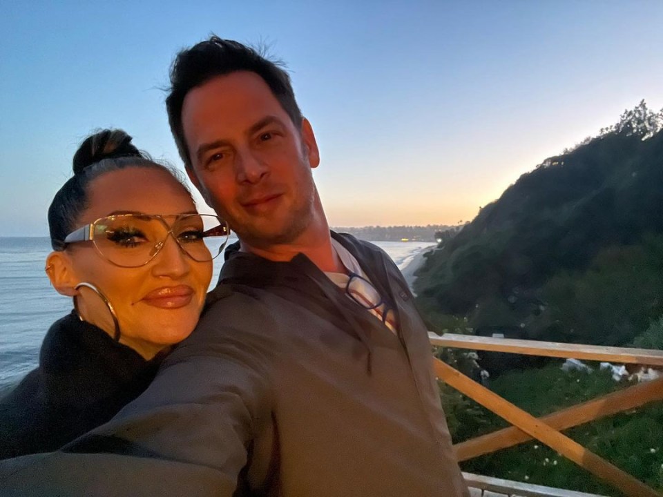 a man and a woman pose for a picture with the ocean in the background