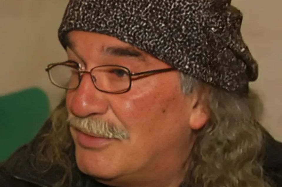 a man with long hair wearing glasses and a hat