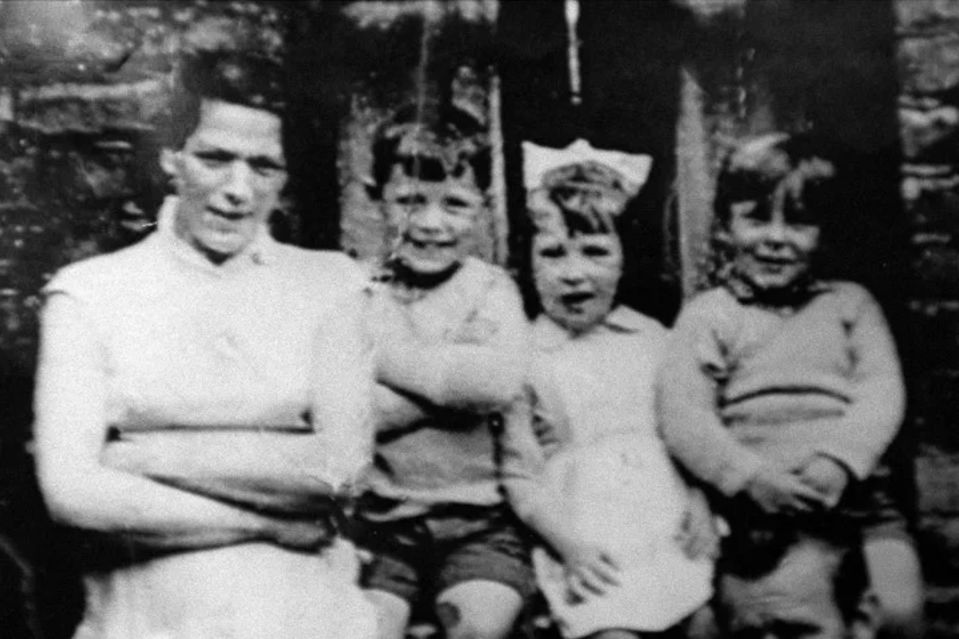 a black and white photo of a woman and three children