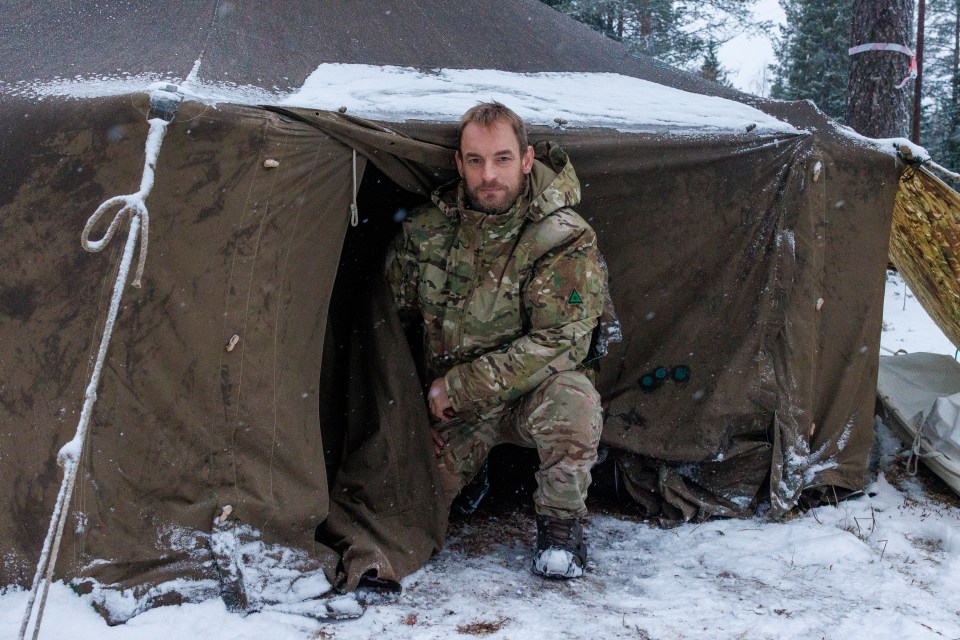 a man in a military uniform is kneeling in the snow