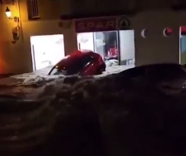 a car is stuck in the water outside of a store .
