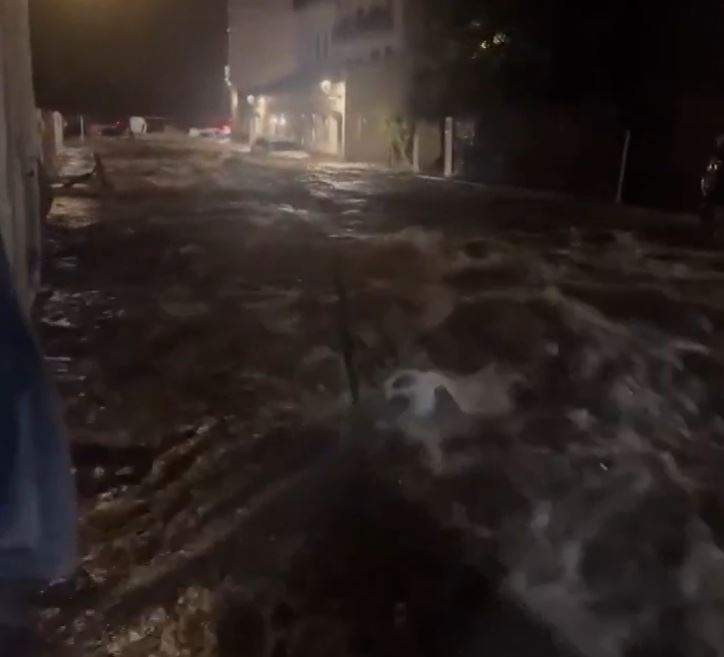 a person is walking down a flooded street at night .