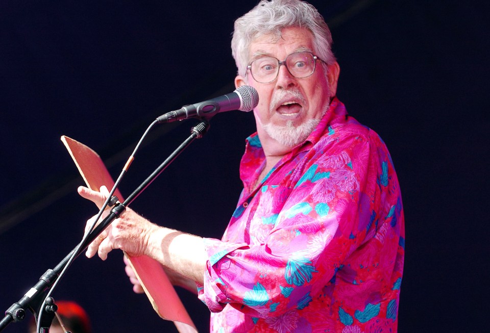 a man in a pink shirt is singing into a microphone