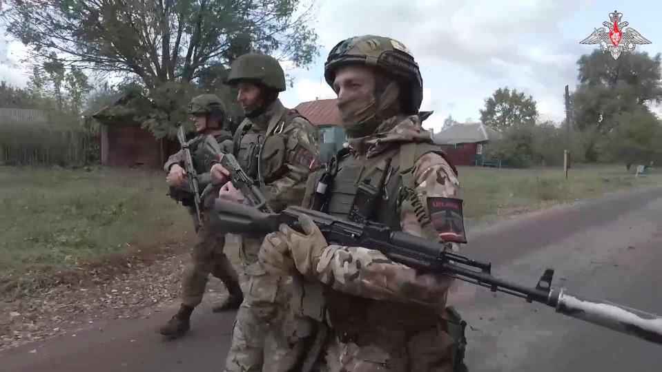 a group of soldiers are walking down a road and one of them has a patch on his arm that says ukrainian