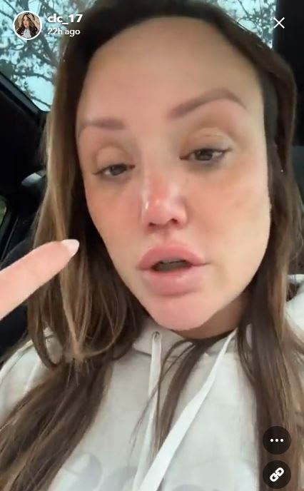 a woman is sitting in a car with her finger pointing at her face .