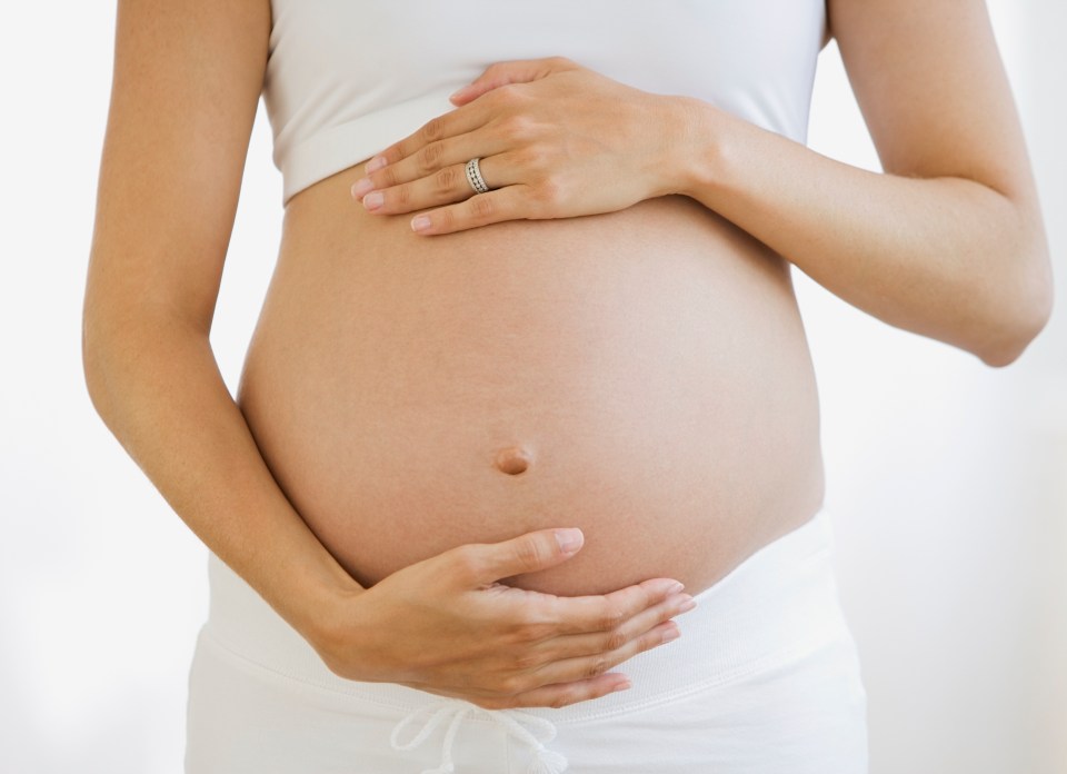 a pregnant woman with a ring on her finger holds her belly