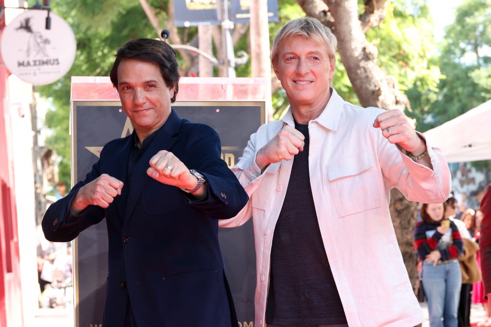 two men standing next to each other on a red carpet in front of a sign that says maximus