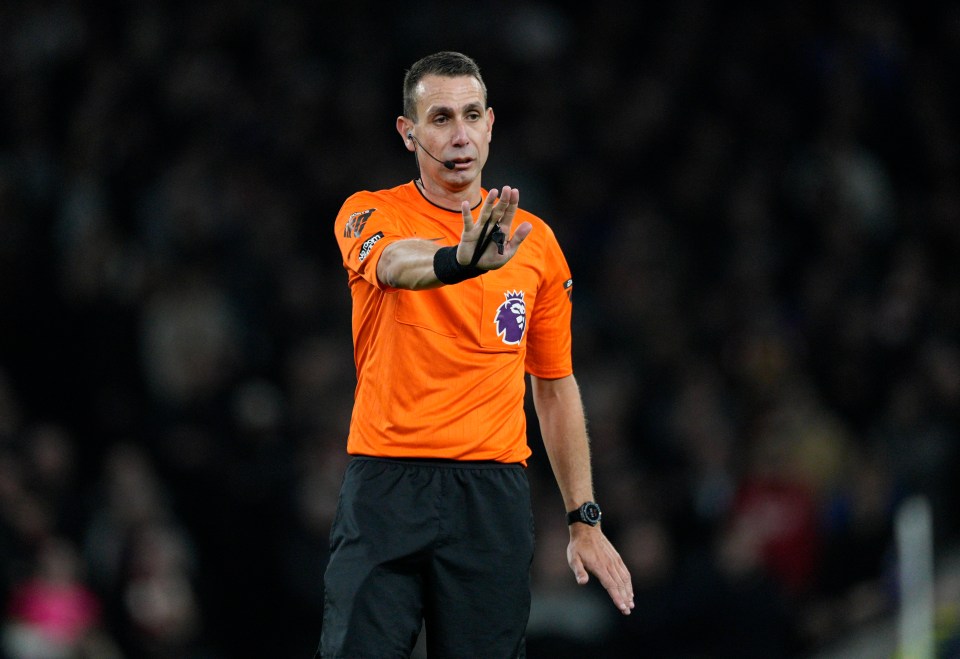 a referee wearing an orange shirt with the word premier league on it