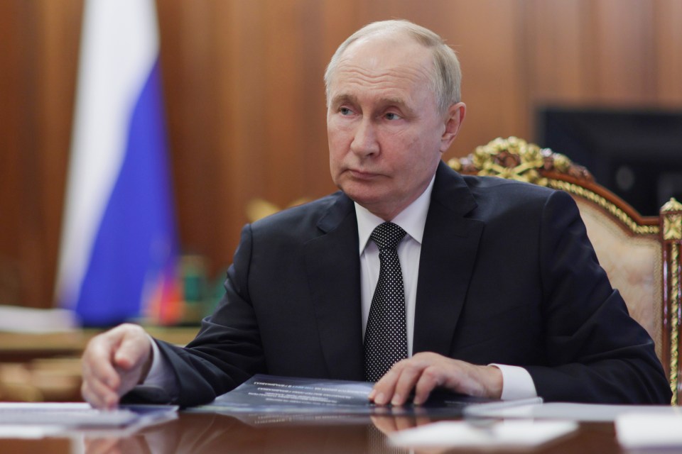 a man in a suit and tie sits at a desk