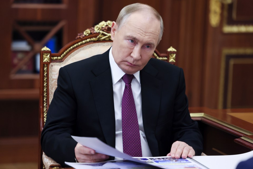 a man in a suit and tie sits at a desk