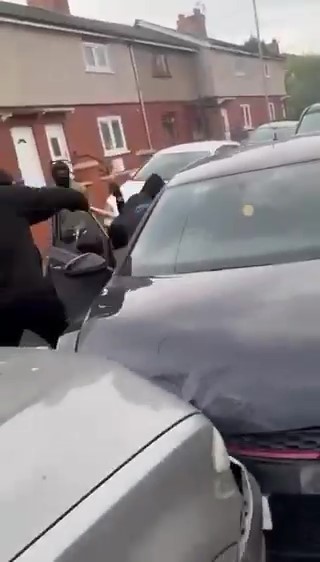 a group of men are standing next to each other in a parking lot .