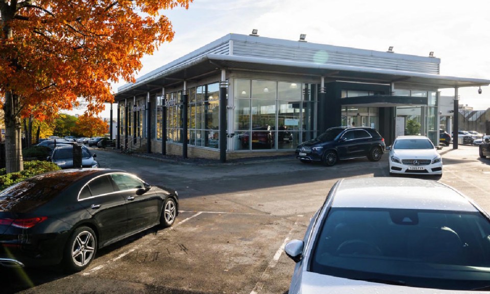 cars parked in front of a mercedes dealership