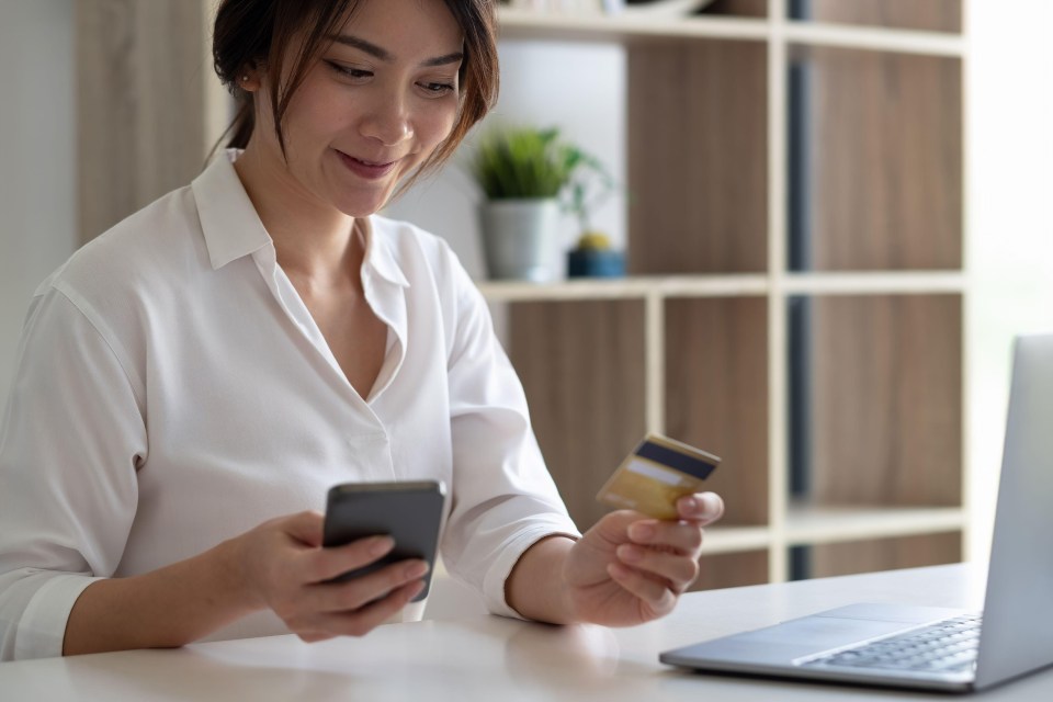 a woman holding a credit card and a cell phone