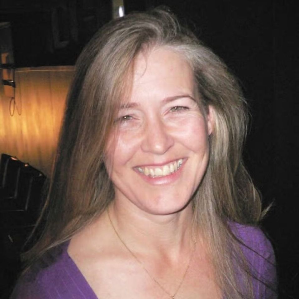 a woman in a purple shirt smiles for the camera