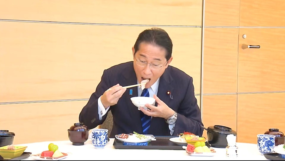 a man in a suit and tie is eating food with chopsticks