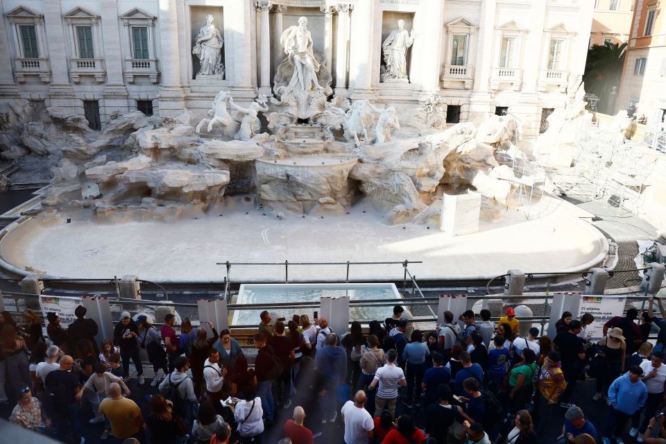 a crowd of people are gathered in front of a fountain
