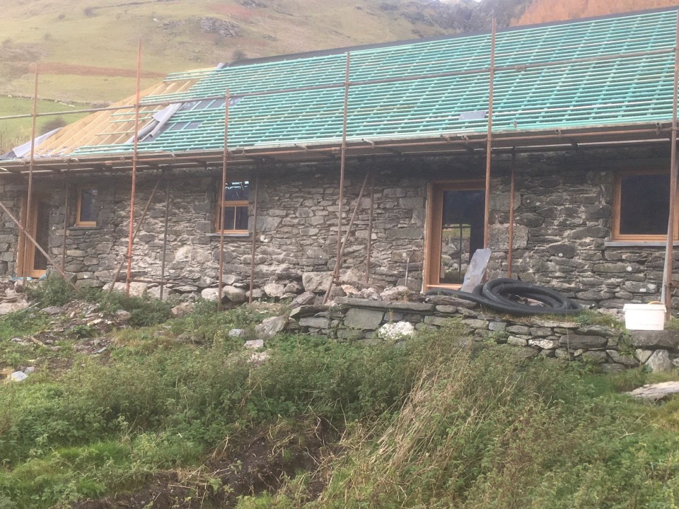 a stone building under construction with a green roof