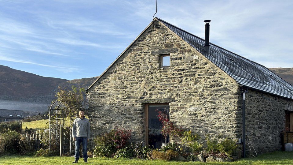 a man stands in front of a stone building