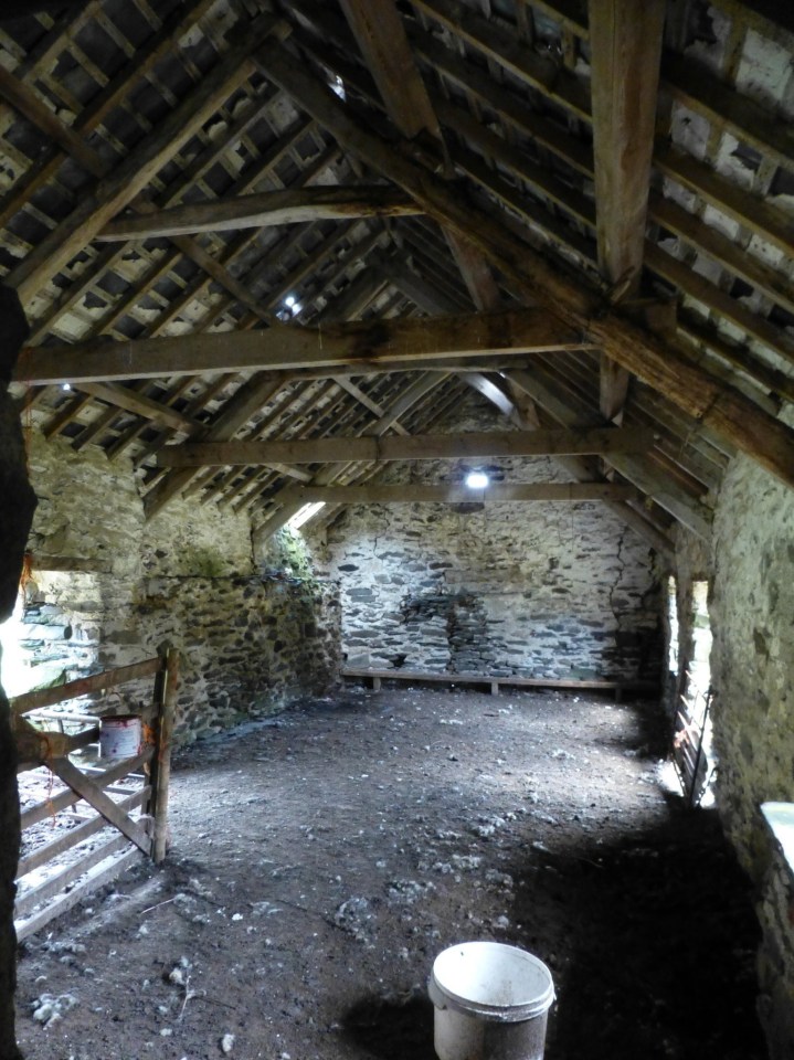 the inside of an old barn with a bucket on the floor