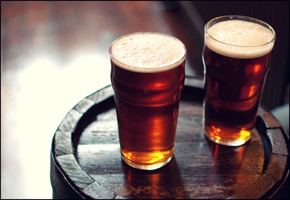 Two pints of bitter ale on a wooden barrel.