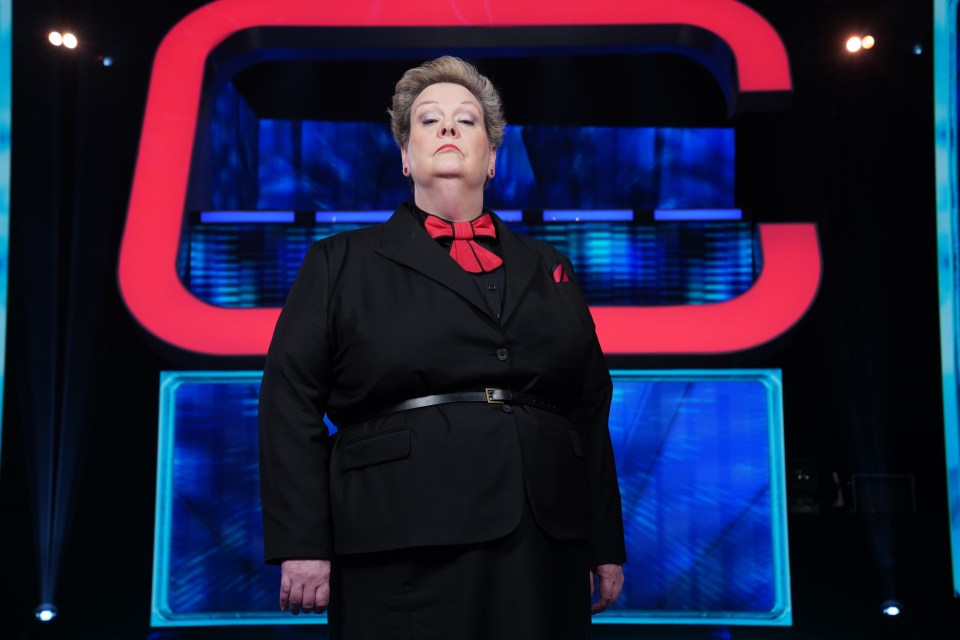 a woman in a black suit with a red bow tie