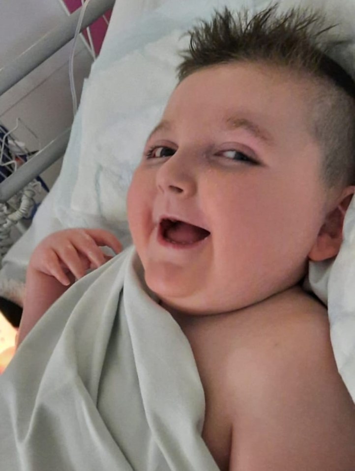 a baby wrapped in a white blanket is smiling in a hospital bed