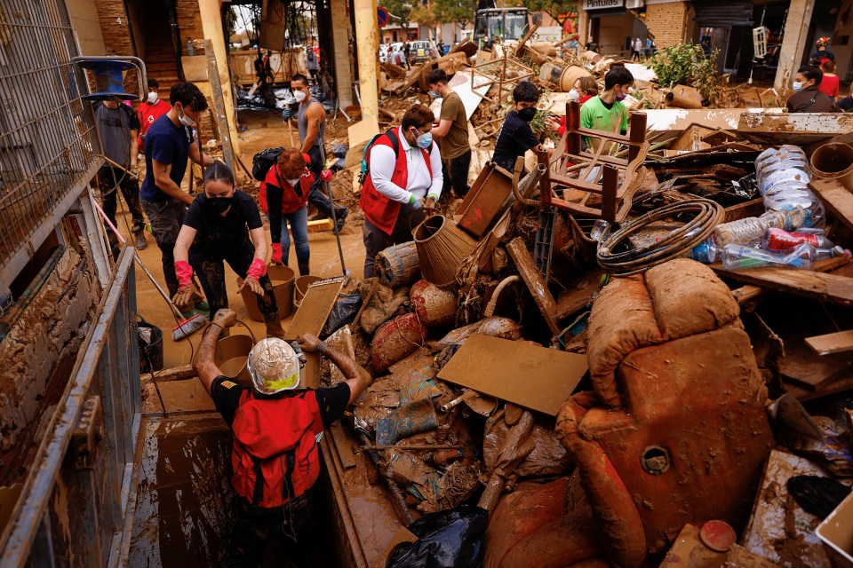 a man in a red vest stands in a pile of trash