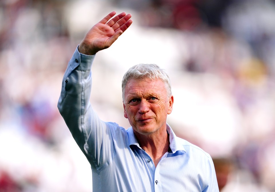 a man in a blue shirt waves his hand in the air