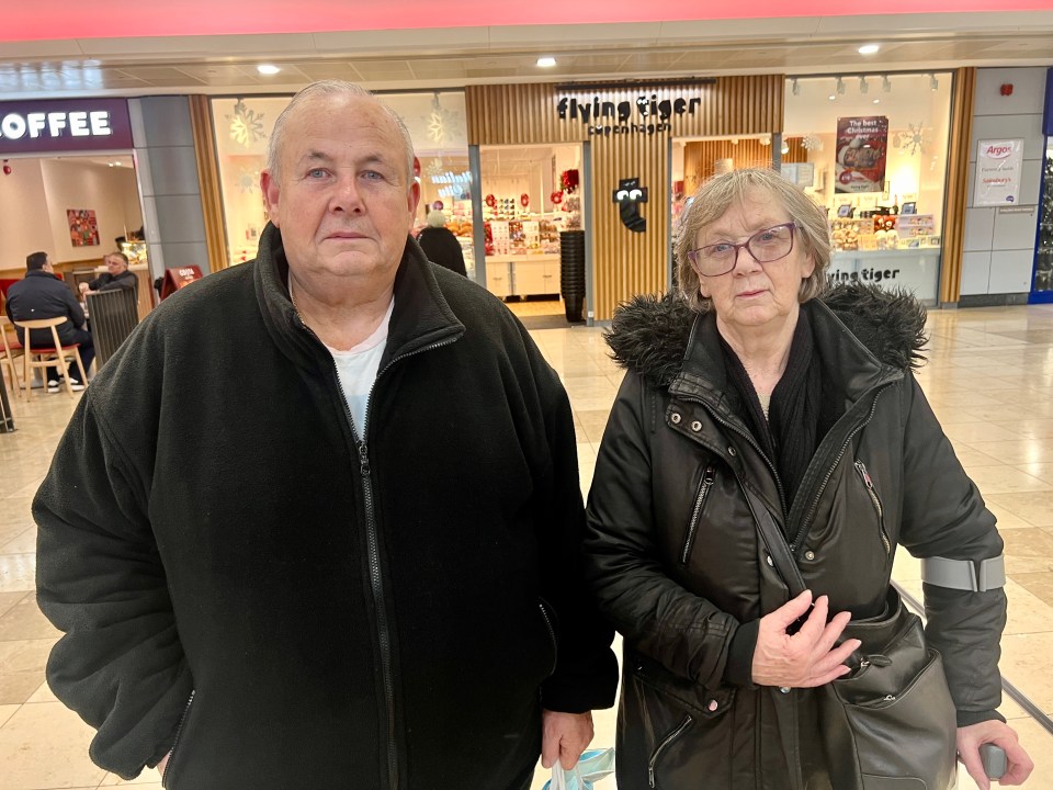 a man and woman stand in front of a store called living tiger
