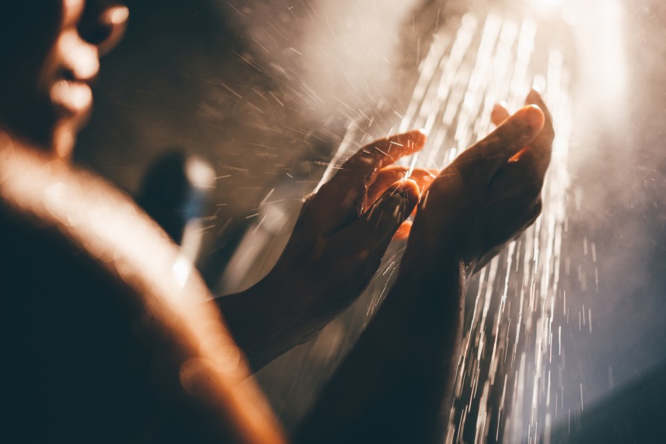 a person washing their hands under a shower head