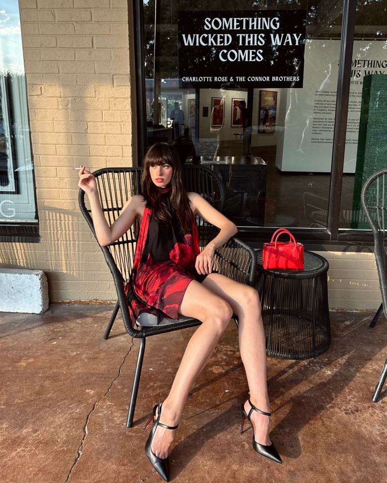 a woman sits in front of a sign that says something wicked this way comes