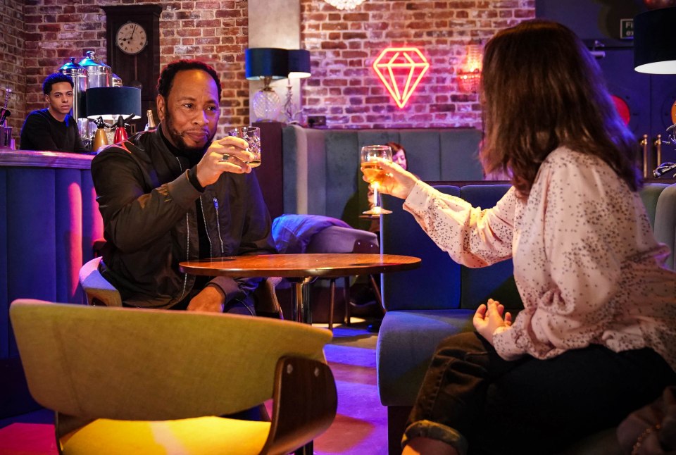 Mitch Baker and Rita toasting drinks in a bar.