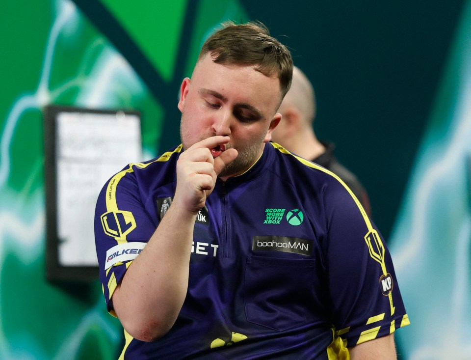 Luke Littler reacts during a darts match.