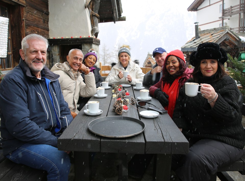 Group of people enjoying hot drinks outdoors in snowy setting.