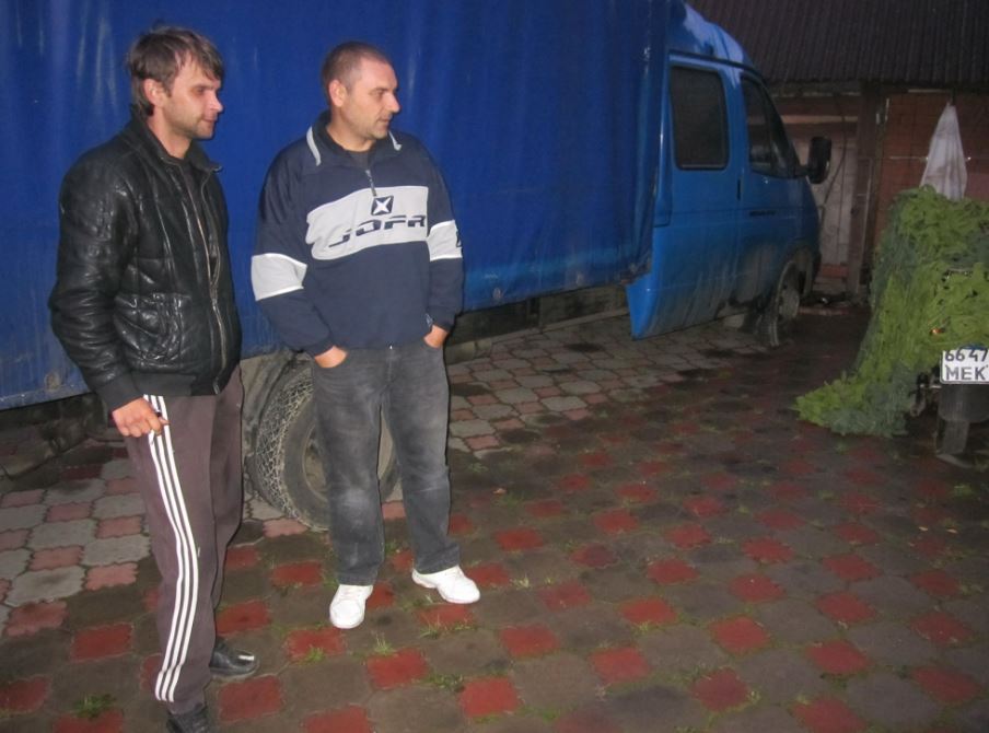 Two men standing near a blue truck.
