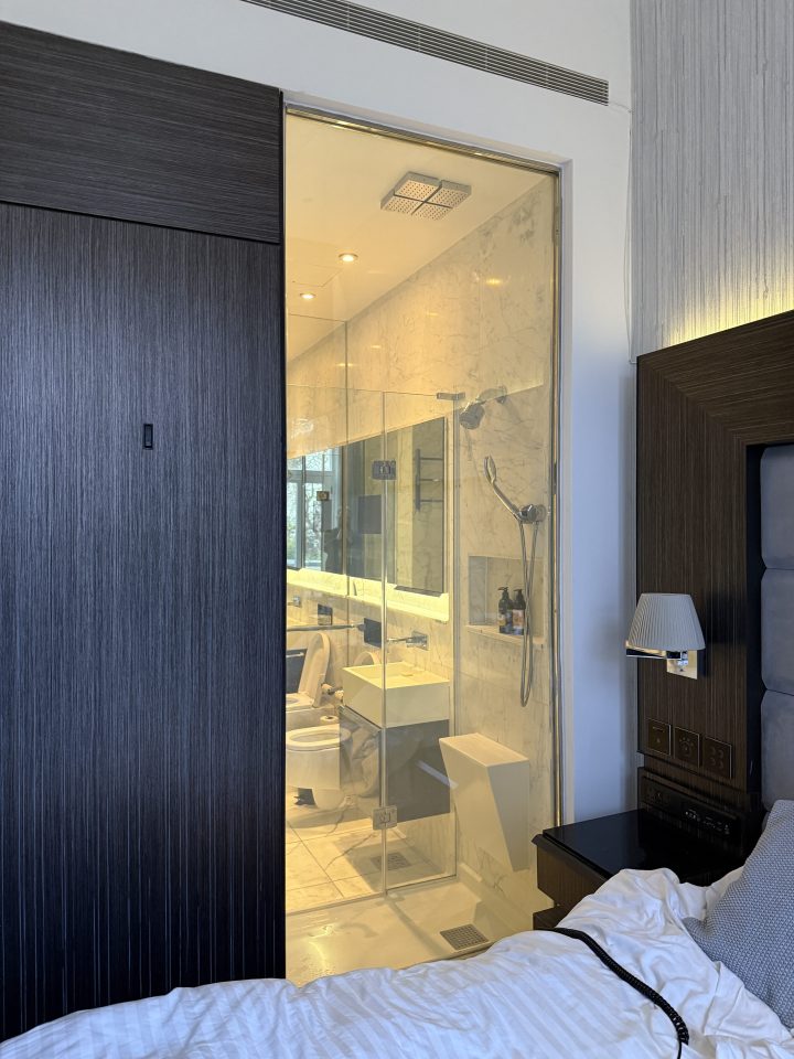 Hotel room with glass-walled bathroom.