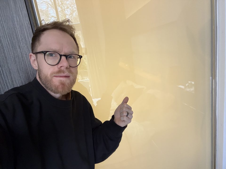 Man gives thumbs up in front of frosted glass.