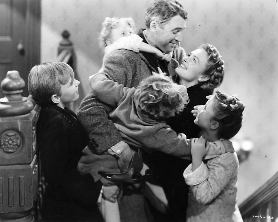 A black and white still from "It's a Wonderful Life," showing James Stewart and Donna Reed embracing their children.