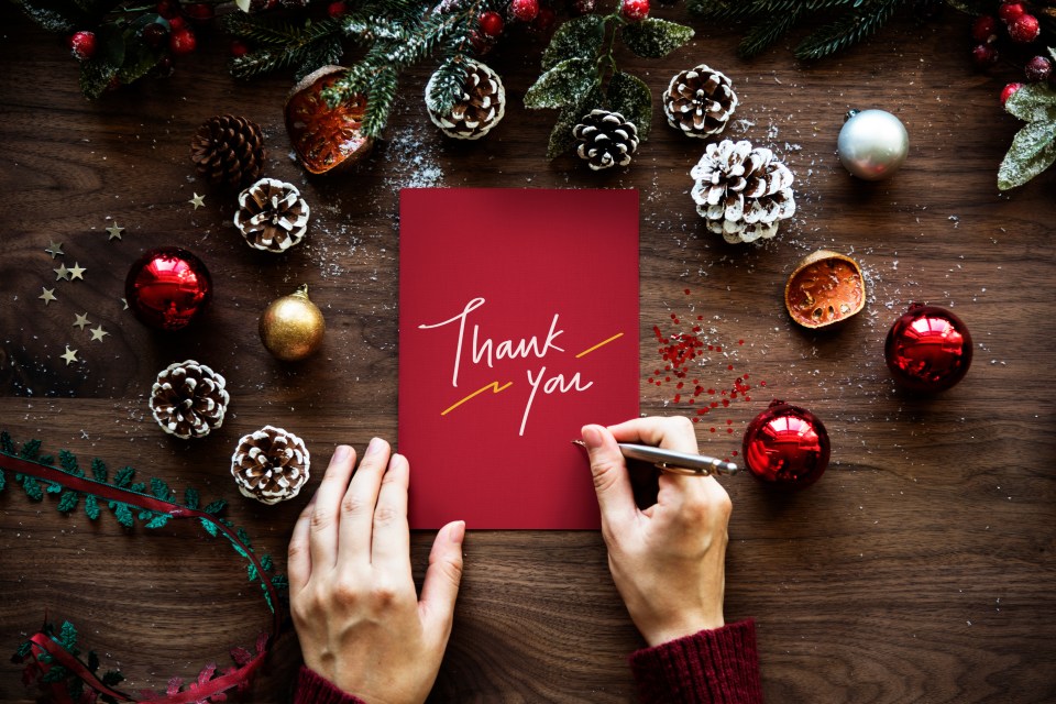 Person writing a Christmas thank you card.