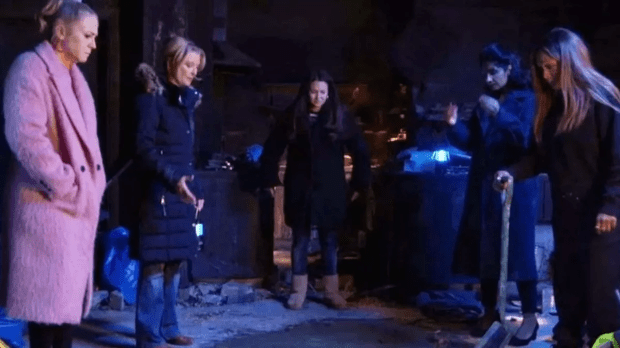 A group of women gather in a dimly lit, derelict space.