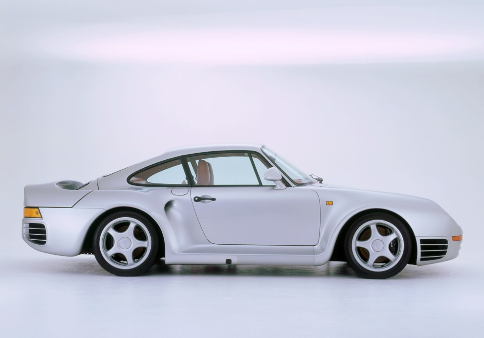 Side profile of a silver Porsche 959 sports car.