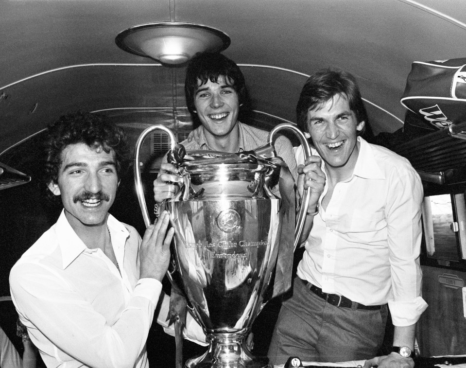 Graeme Souness, Alan Hansen, and Kenny Dalglish holding the European Cup trophy on a train.