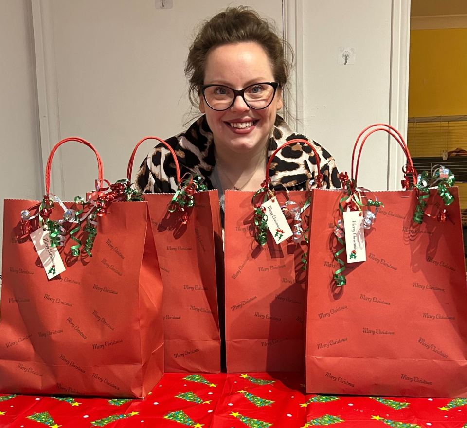 Woman holding four Christmas gift bags.