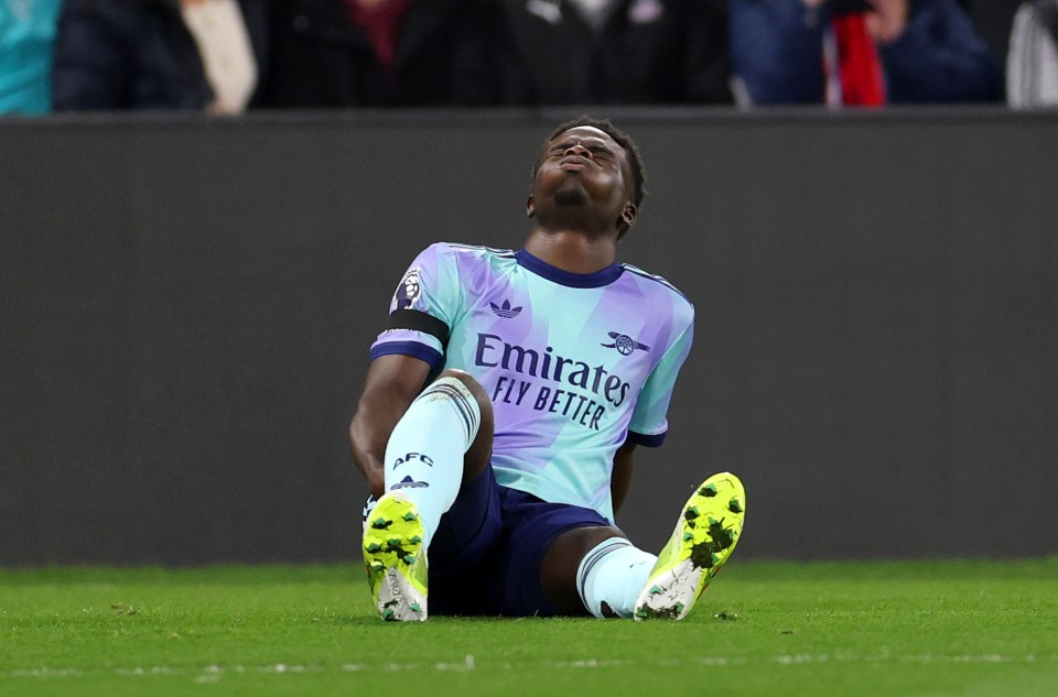 Bukayo Saka of Arsenal in pain on the field after an injury.